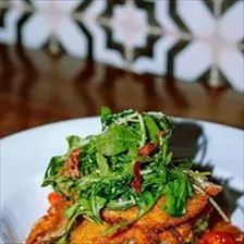 BLVD Chicken Pesto with parmesan crusted chicken, pesto cream sauce, bacon, and arugula over herb spaghetti at BLVD Grille
