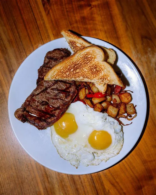 Grilled steak, two fried eggs, home fries, and toast
